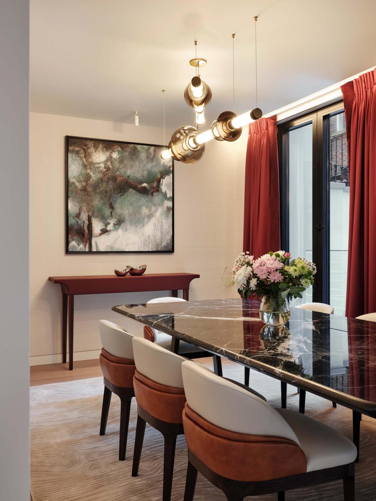 Gabriel Scott Luna glass chandelier illuminating marble dining table with rust and cream dining chairs
