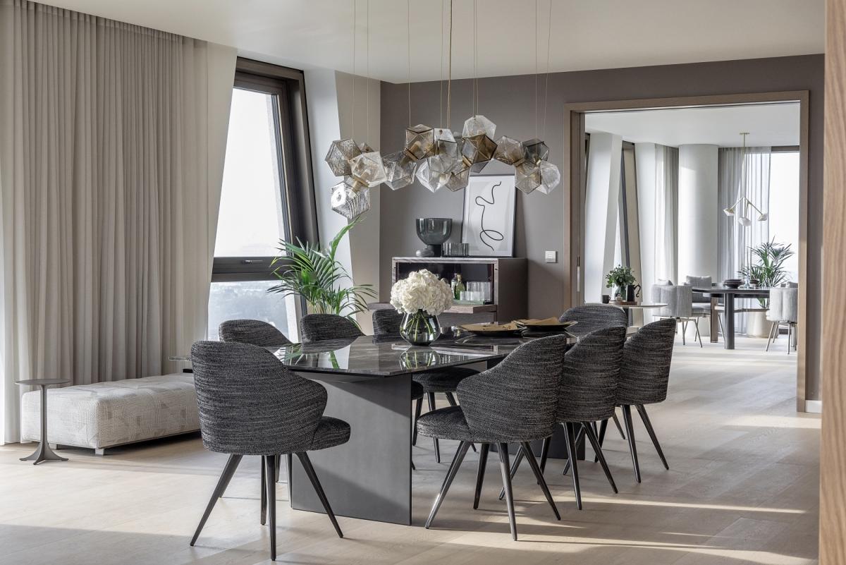 Long glass chandelier by Gabriel Scott, suspended above a dining table in feature penthouse interior design.